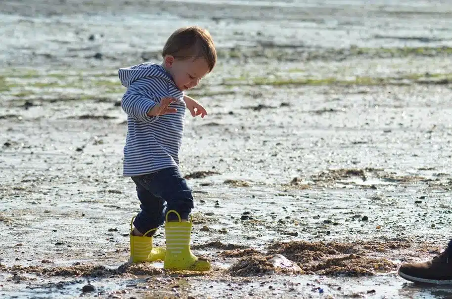 Un enfant avec des botes jaunes à la plage