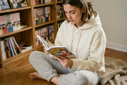 Jeune femme lisant un manga assis sur le sol de sa chambre entourée de livres